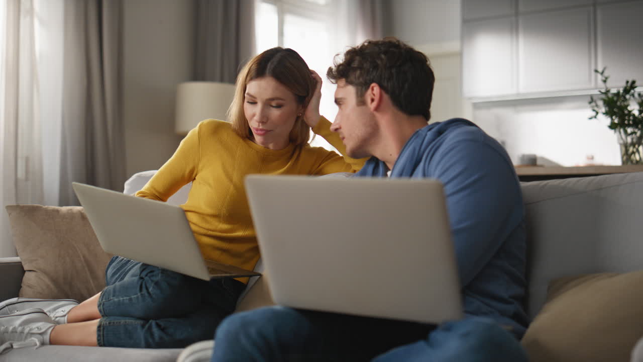 Young couple cooperating computers at living room closeup. Colleagues working