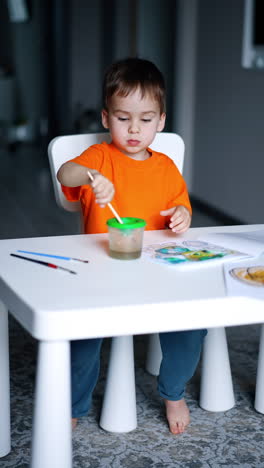 adorable baby boy is focused on painting at home. toddler kid having art hobby. vertical video.