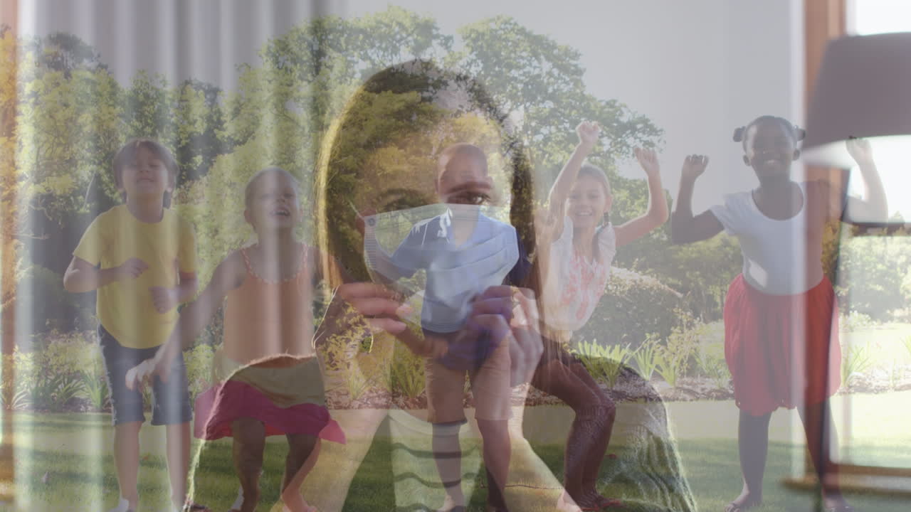 정원에서 함께 점프하는 다양한 아이들의 그룹에 대항하여 얼굴 마스크를 착용한 백인 여성