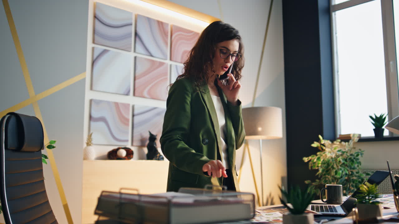 Forretningskvinde har telefonsamtale stående på kontoret. Kvinde taler i telefon.