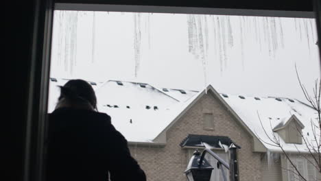 woman knocks icicles off gutters in slow motion by throwing a piece of ice