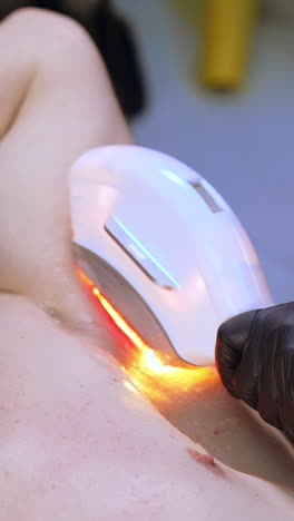 man in goggles lying with hands under the head. apparatus for laser epilation is moved by the armpit zone. close up. vertical video