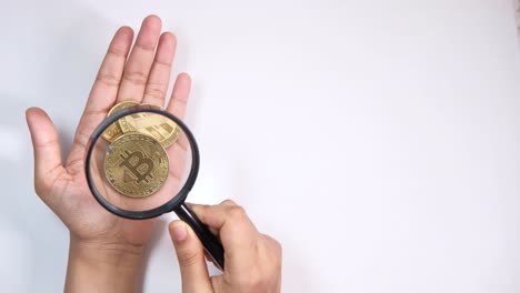 monedas de bitcoin bajo una lupa en una mano