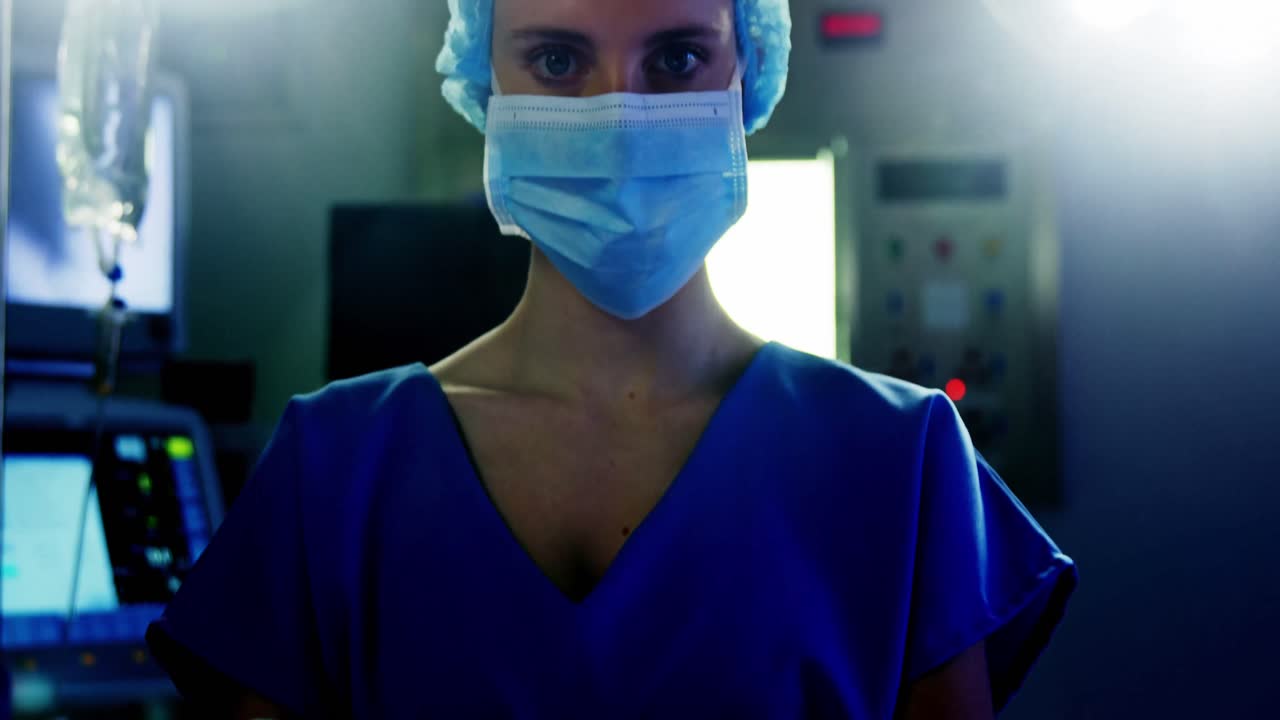 Ritratto di chirurgo donna in piedi con le braccia incrociate in sala operatoria
