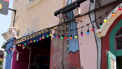 camera pans over vibrant urban mural and string lights on colorful building facade in daylight