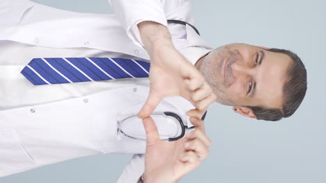 Vertical-video-of-Doctor-making-heart-looking-at-camera.