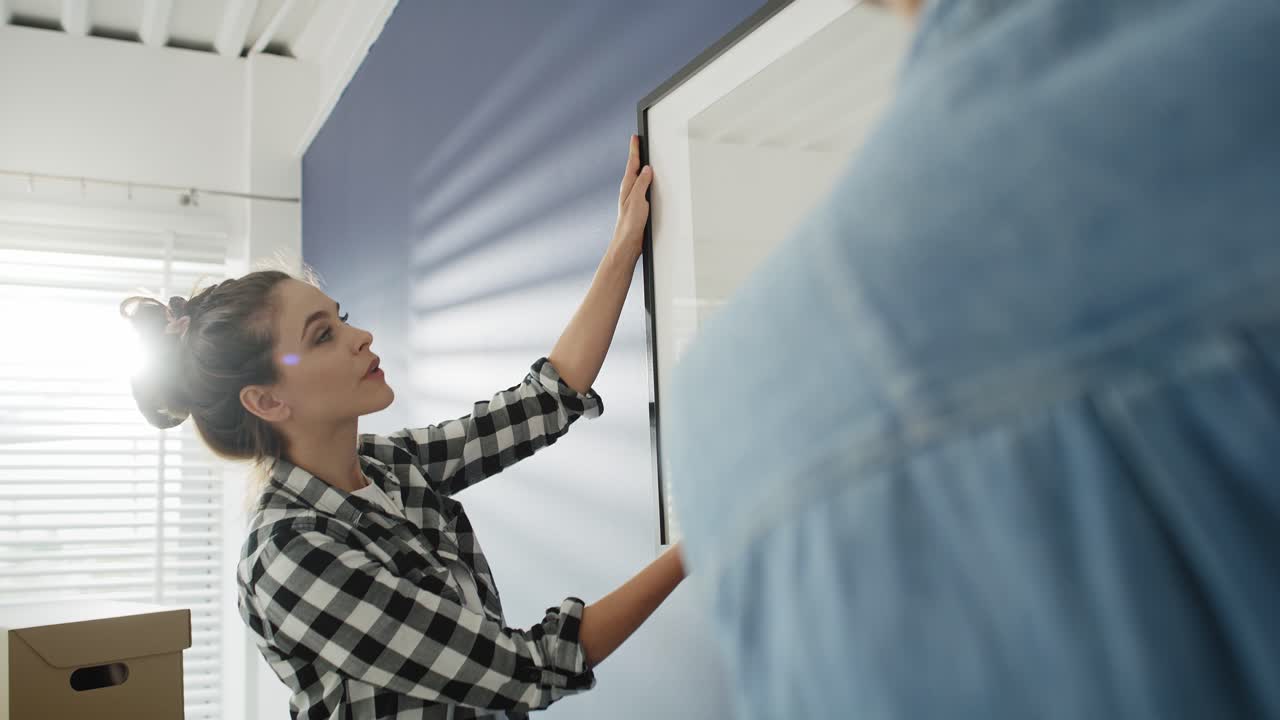 seguimiento de video de una pareja colgando un marco de fotos juntos.