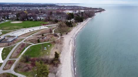 Drone-flying-along-lake-coastline-in-spring