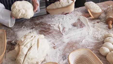 diverse bakers working in bakery kitchen, cutting dough for bread in slow motion