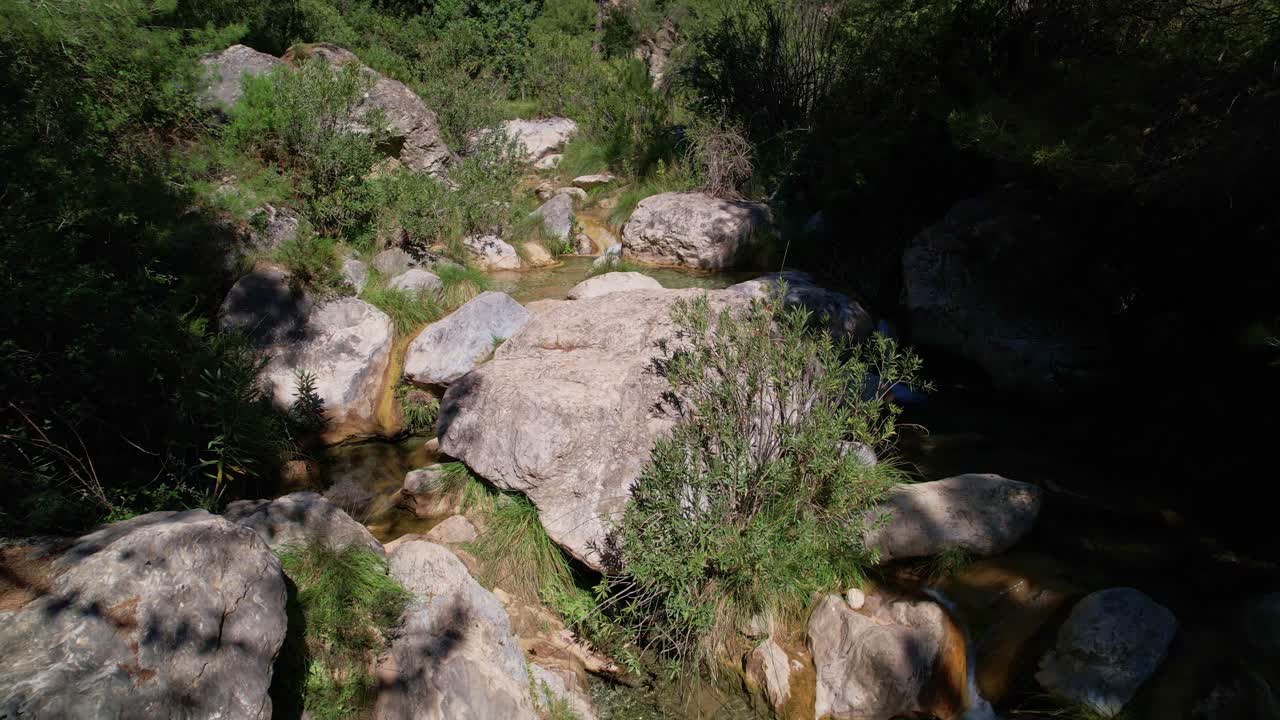 vista aérea de bajo nivel de un arroyo de alta montaña y un río dentro del bosque