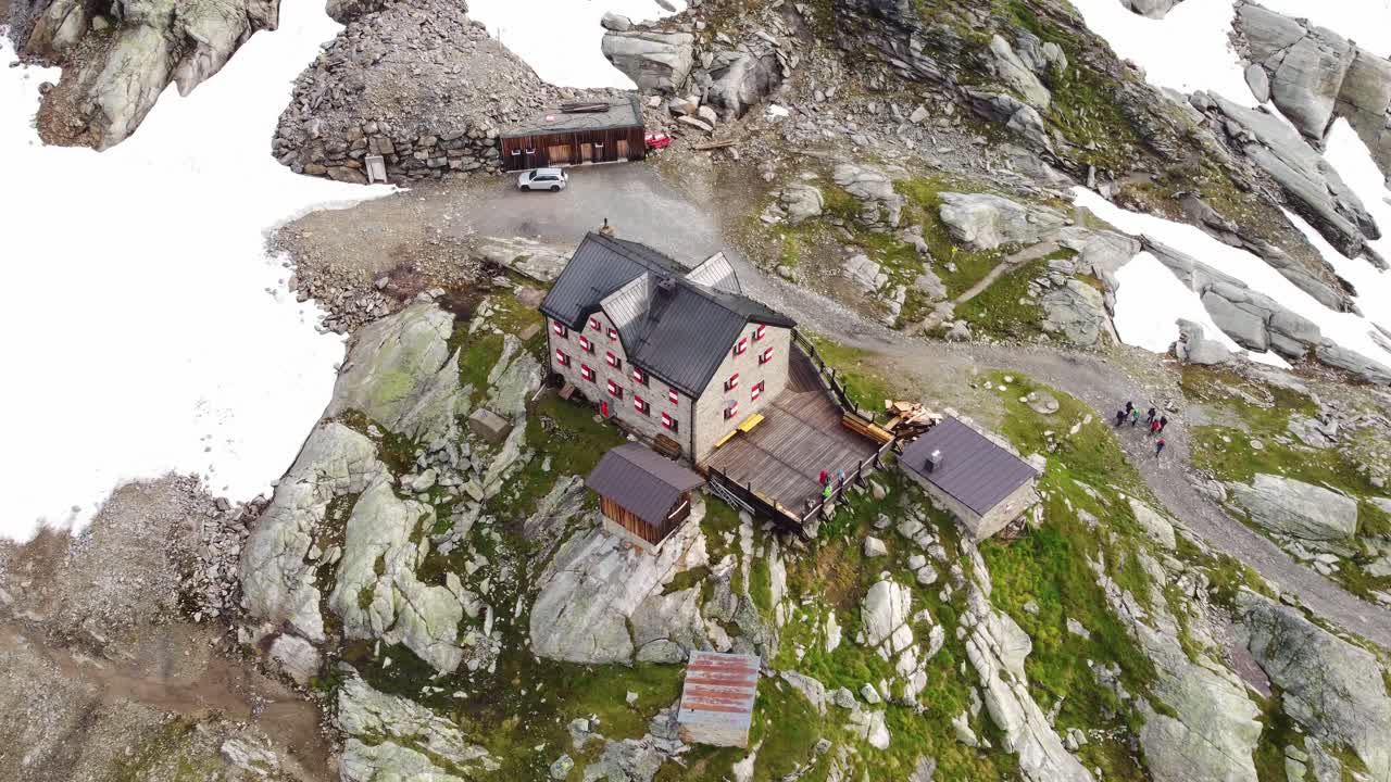 casa grande en una roca enorme rodeada por unos pocos campos de nieve en los alpes en kaernten, austria