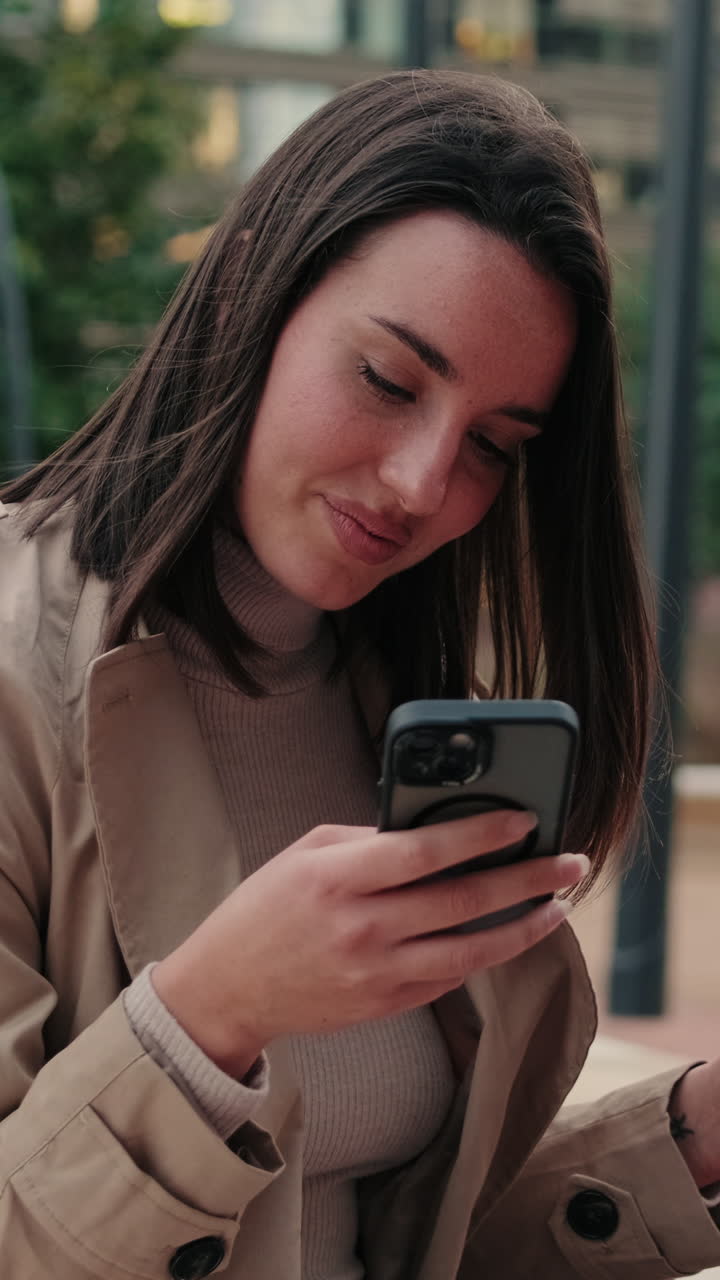 Giovane donna che sorride mentre usa il suo smartphone all'aperto