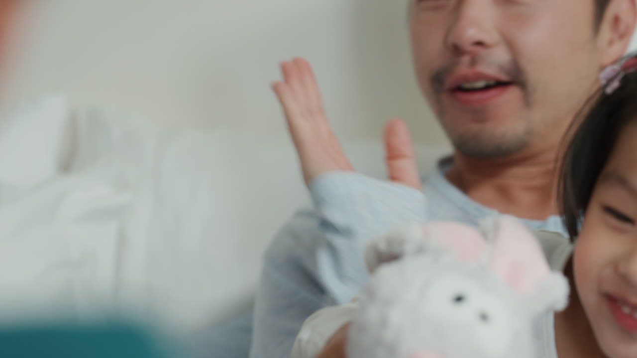 행복한 아시아 가족과 아이들이 침대에 뛰어들고 엄마와 아빠와 함께 놀고 주말 아침에 재미를 느끼고 흥분된 어린 아이들이 부모와 함께 집에서 게임을 즐기고 있습니다. 4k 영상