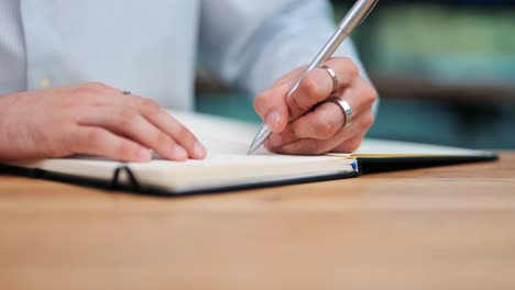 strategic brainstorm: man's ringed hand writing on paper in business setting