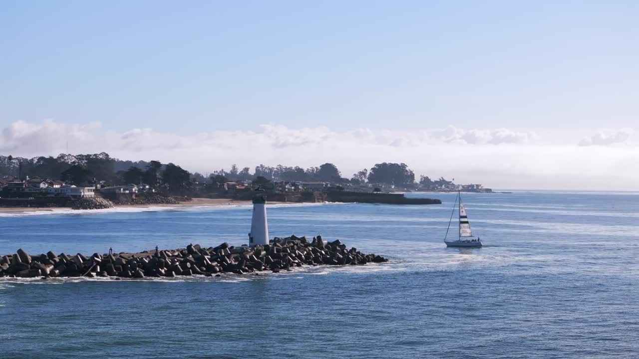 Walton Lighthouse sailboat Monterey Bay Santa Cruz California USA aerial drone landscape deep blue Pacific Ocean seagull pelican birds harbor jetty morning blue sky mist fog parallax circle right
