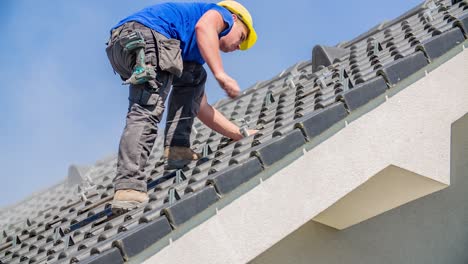 Young-worker-screwing-long-screw-into-wooden-roof-construction