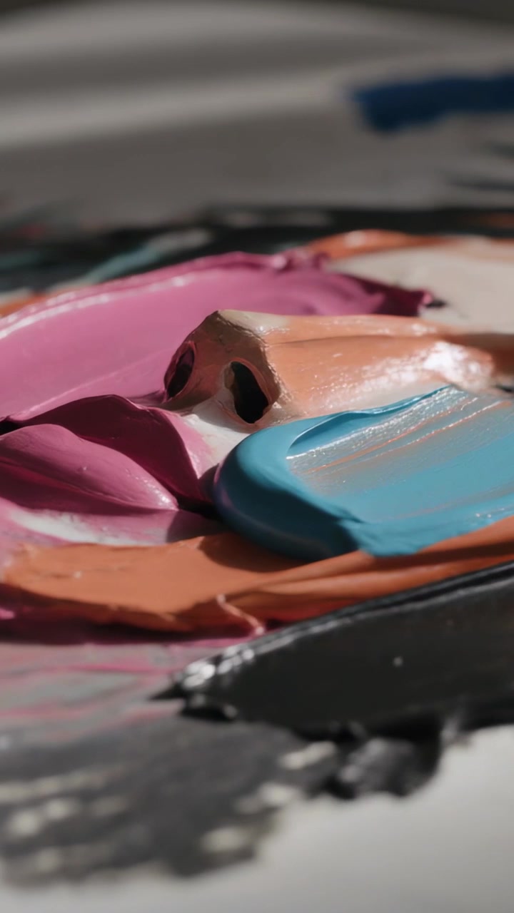 Video verticale: Coltello che entra con pittura blu stesa, fondendosi su naso e labbra a impasto su un tavolo.
