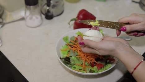 Weibliche-Hände-Schneiden-Ein-Ei-Zu-Einem-Salat-Mit-Roter-Paprika-Und-Salat