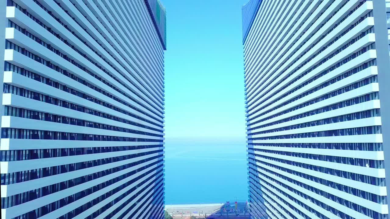 드론은 유리 창문이 있는 두 건물 사이를 날아갑니다.