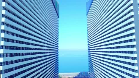 the drone flies between two buildings with glass windows.