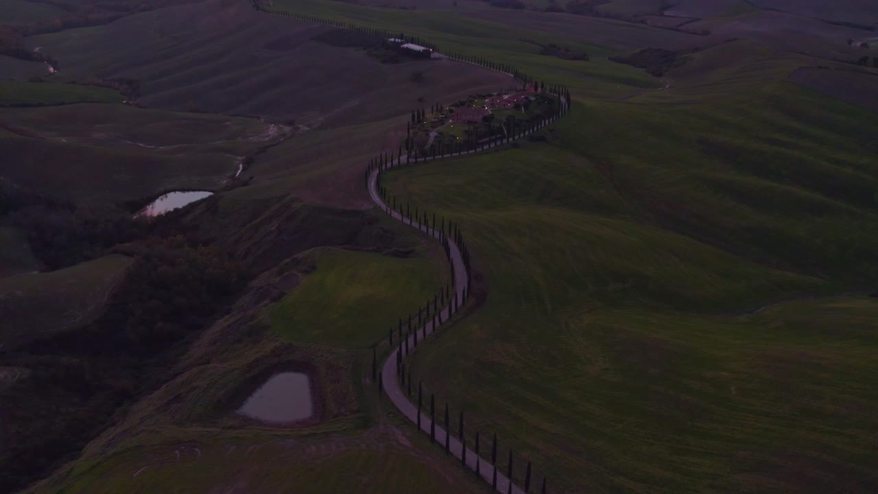 Tramonto su un viale di cipressi nelle dolci colline della Toscana, aerea.