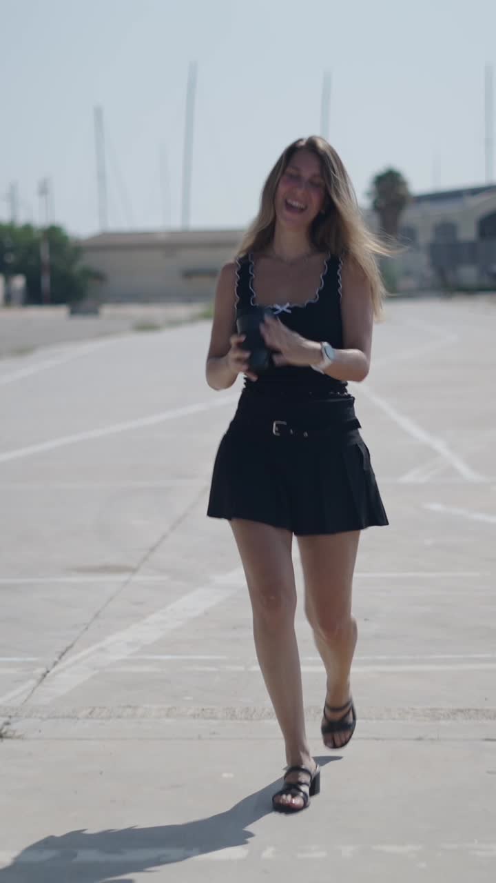 Donna con abito nero che cammina e beve