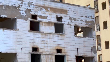 weathered exterior of derelict building with broken windows and peeling paint. perfect for urban decay, war zone, or crisis concepts.