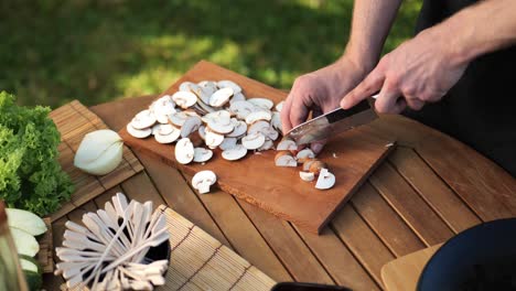 Junger-Mann-Schneidet-Pilze-Auf-Einem-Holzbrett-Im-Hohen-Winkel-Des-Gartens