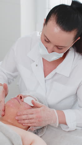 cosmetologist applying special moisturizing cream scrub peeling face of pretty caucasian woman girl