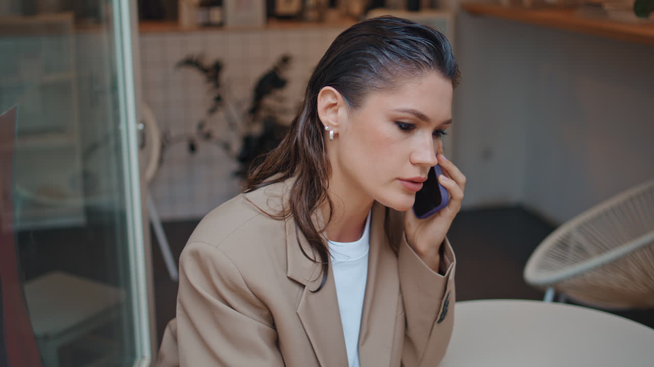 비즈니스 레이디가 드폰으로 얘기하고 테이블에 앉아 있고 작은 카페테리아가 혼자 닫혀 있습니다.