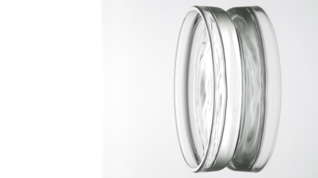 회색 방울은 파동을 일으키는 액체와 함께 페트리 접시에 떨어집니다.