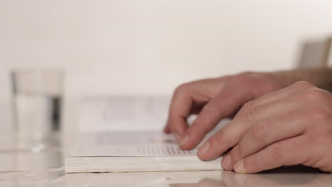 Mano-Masculina-Volteando-Las-Páginas-Del-Libro-Durante-La-Lectura