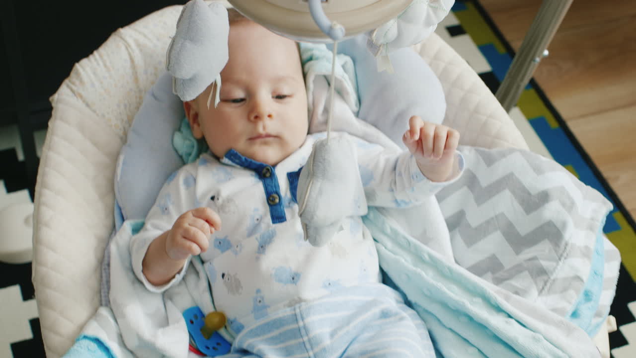 Il piccolo di due mesi è nella culla. Non dorme. Primo piano sorridente.