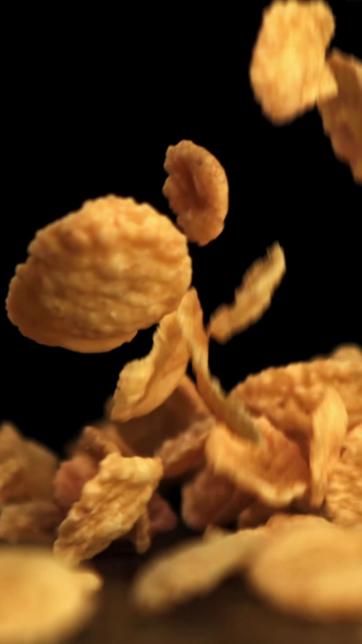 Cornflakes dorati che cadono al rallentatore su uno sfondo nero