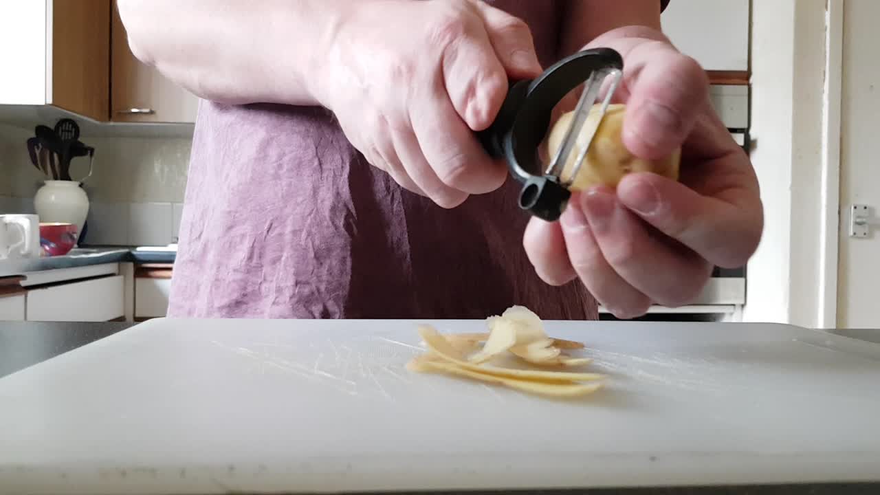 Uomo con dito indice parzialmente amputato sulla mano destra sbuccia una patata