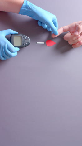 vertical video of hands of caucasian doctor and patient checking blood sugar level, slow motion