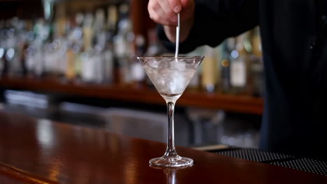 bartender stirring a cocktail in a martini glass at a bar