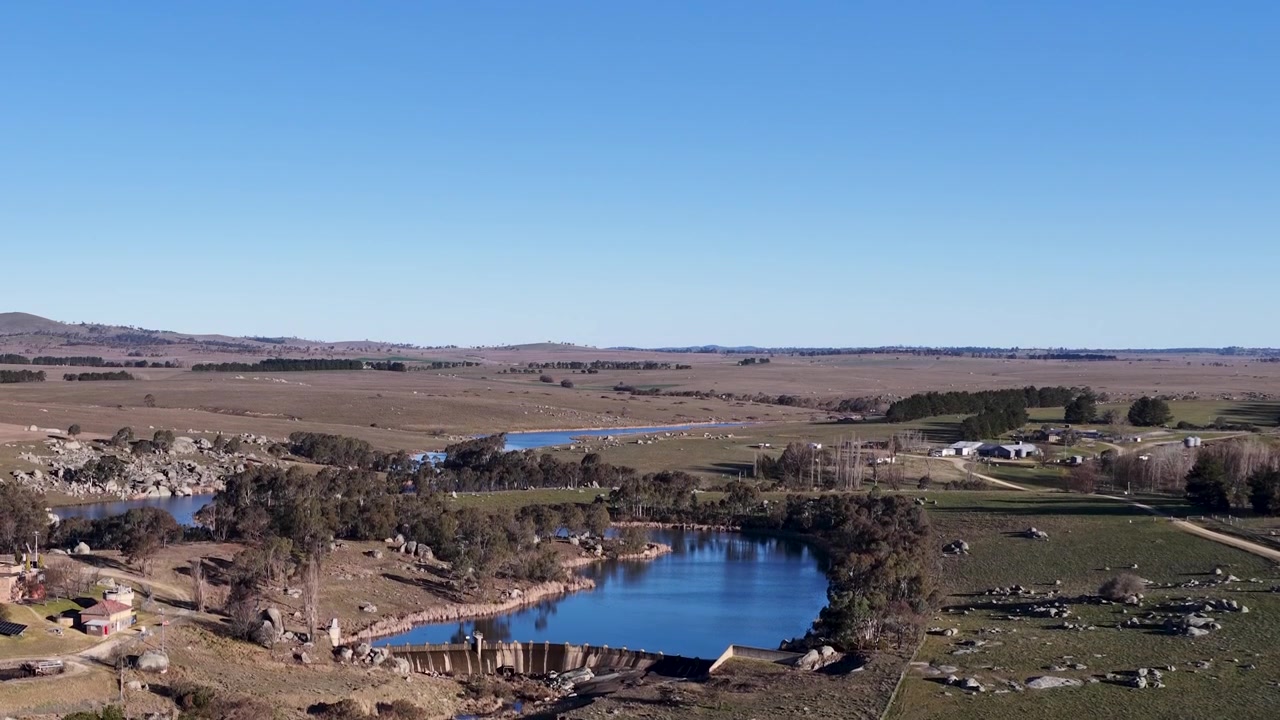 Ampia ripresa aerea di una diga blu circondata da terreno roccioso dell'outback a Uralla, Australia