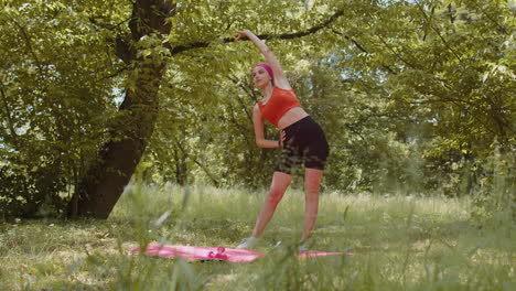 Sporty-young-woman-athlete-doing-stretching-fitness-tilts-exercises-workout-outdoors-in-sunny-park