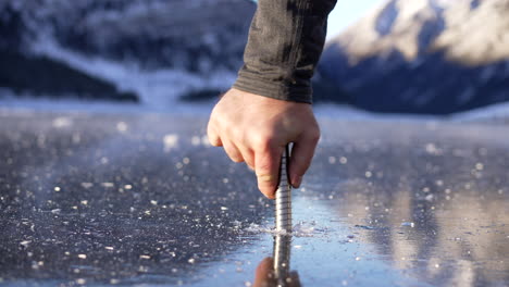 checking thickness of lake ice with an ice screw.