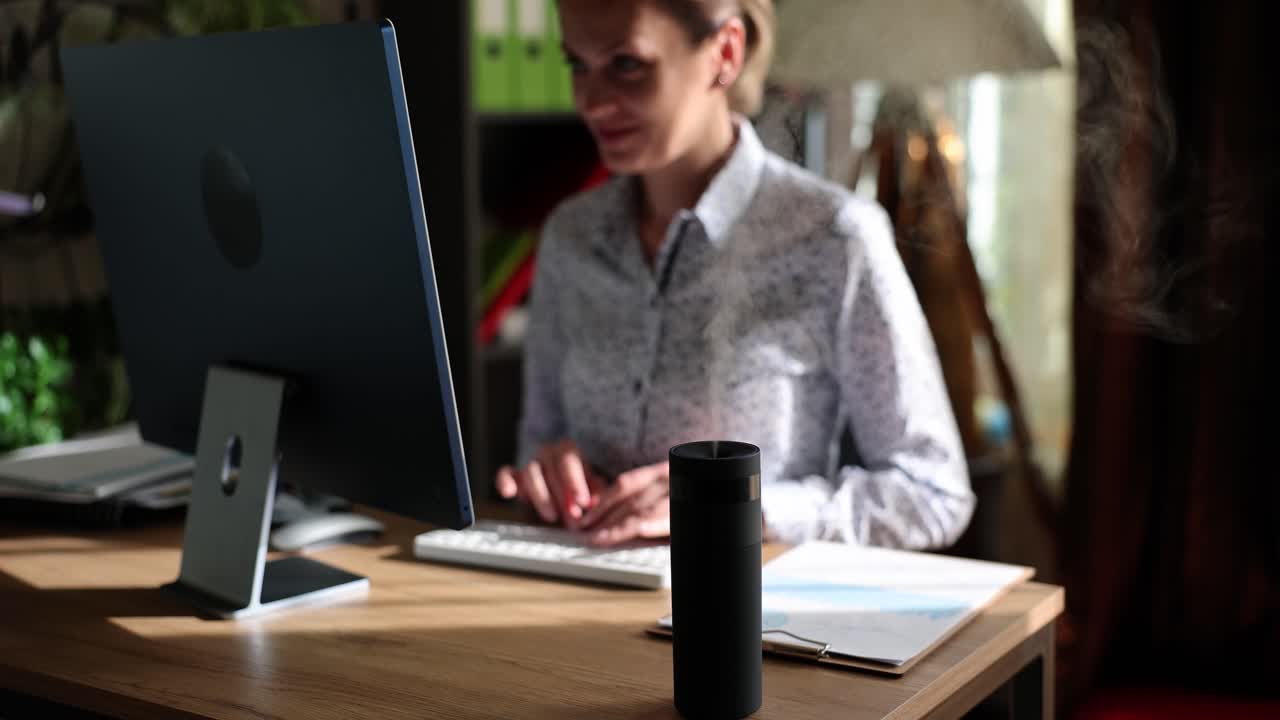 Woman working on computer at desk with smart speaker or diffuser