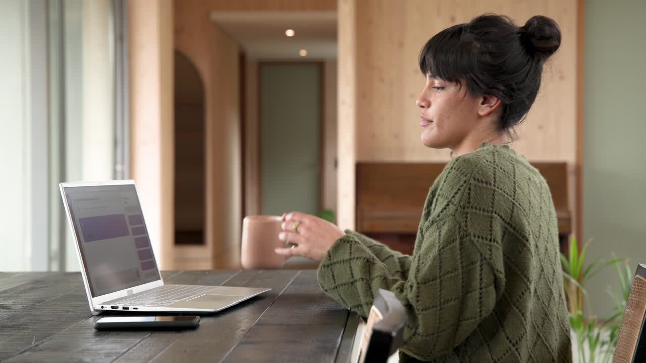 Woman in cozy sweater enjoying hot drink by window at home