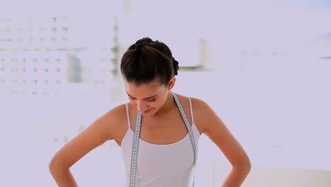 Cheerful-beautiful-woman-wearing-a-measuring-tape-and-giving-thumbs-up