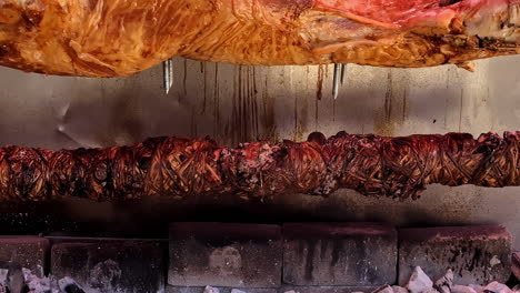 primer plano de cordero y kokoretsi siendo asado sobre carbón