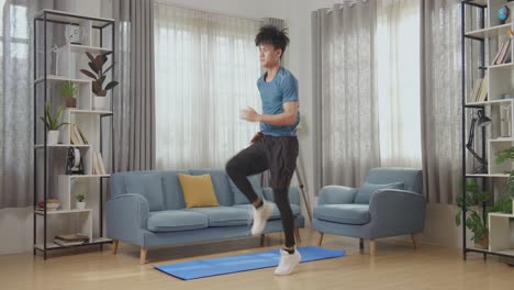 hombre de fitness atlético asiático en ropa deportiva está corriendo enérgicamente en su lugar en su sala de estar con interior moderno