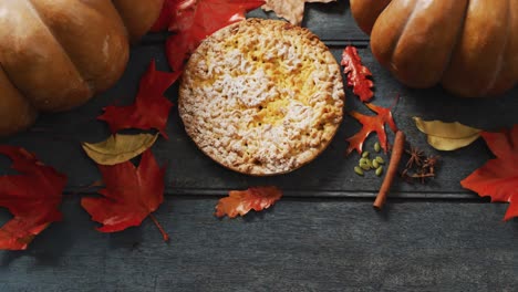 video of autumn leaves, pumpkin, spices and pie on wooden background