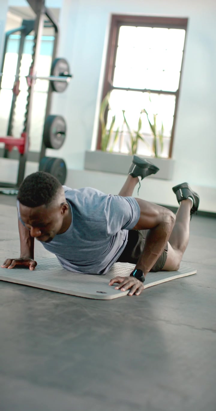 Vertical video: Coach is cueing trainee sliding forward then lowering chest into pushups on mat