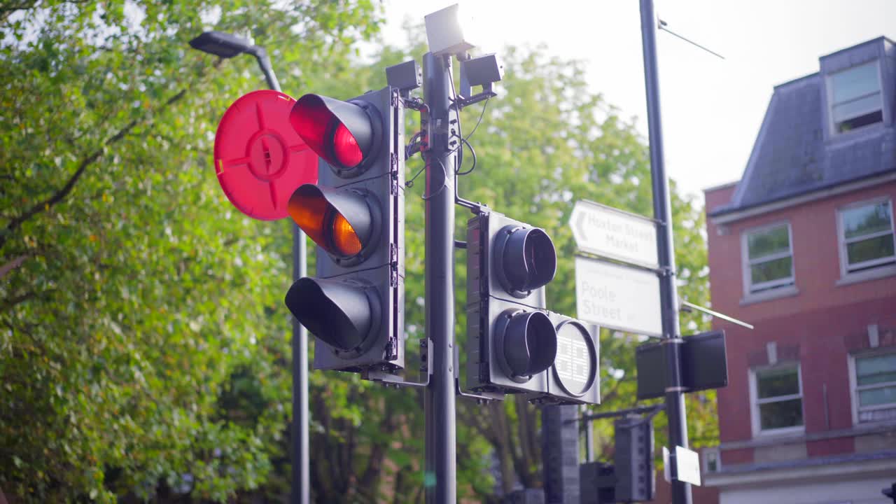 la luz roja se vuelve naranja y verde, en una carretera londinense junto a un parque