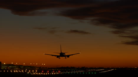 silueta de avión aterrizando en el aeropuerto de barcelona durante la puesta de sol