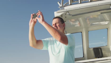 side view of a caucasian man on boat taking photos with his phone